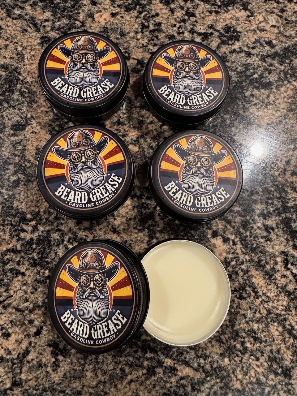 Tins of Beard Grease, an all-in-one beard oil, butter, and balm, with one tin open